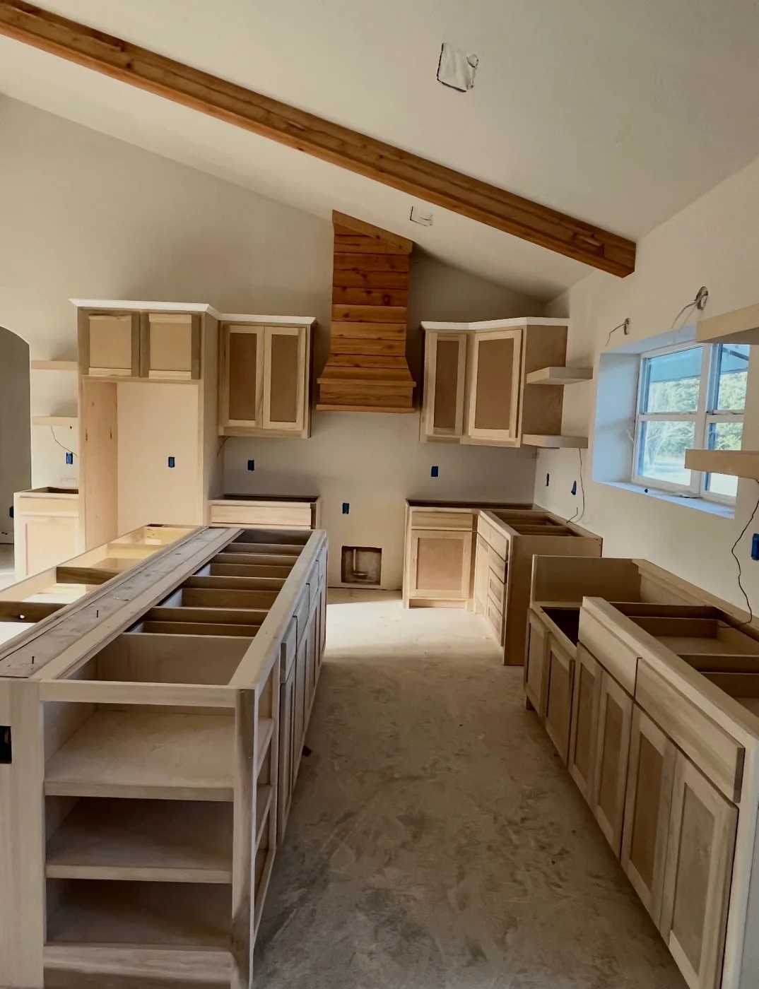 Kitchen island and perimeter cabinetry beneath wood ceiling beams